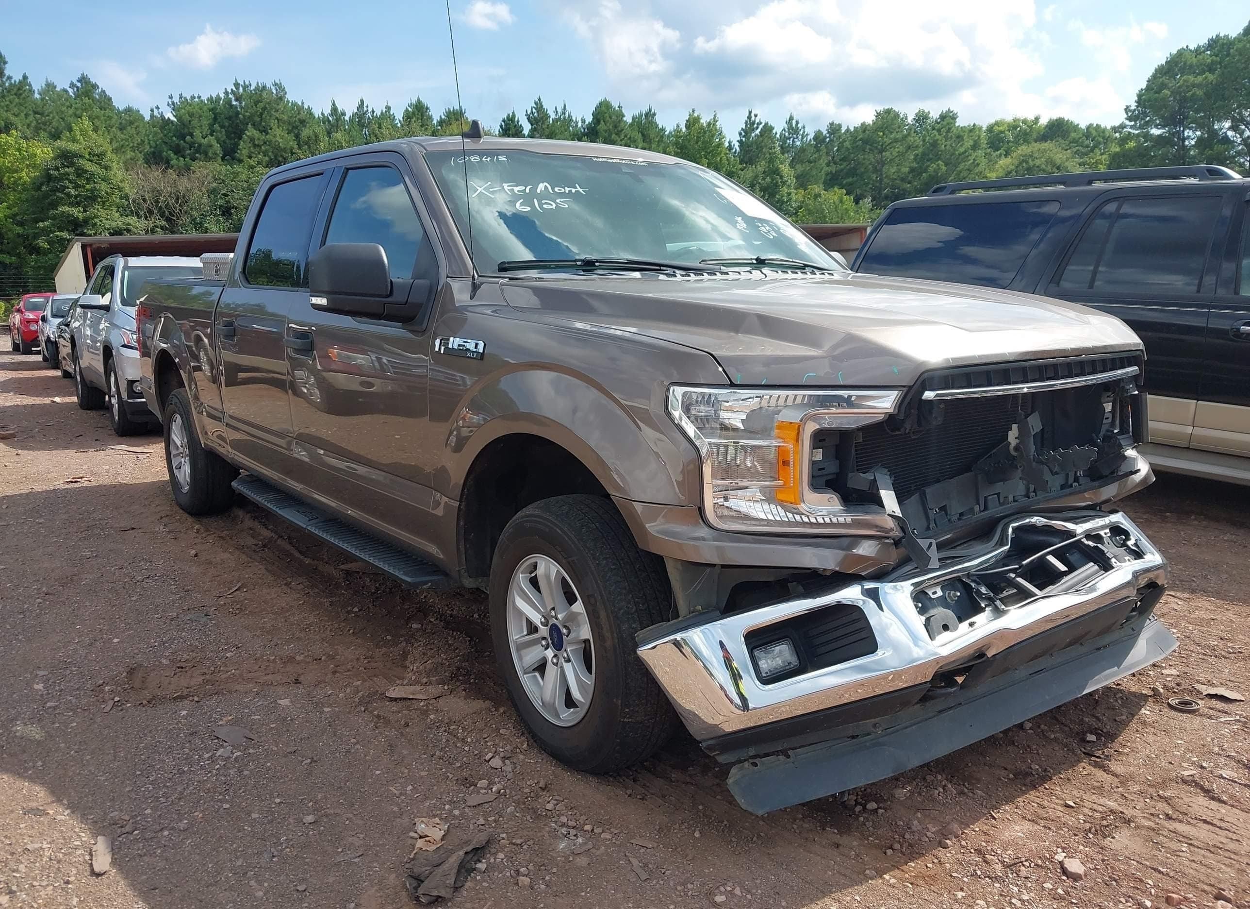 Ford F-150 auction lot, front three-quarter view — missing bumper, exposed headlight bracket, disassembled front-end after collision