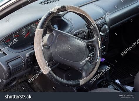 Worn steering wheel and faded leather on a high-mileage used car interior